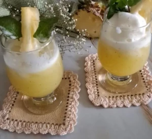 Two glasses of fresh pineapple juice with mint served on a marble counter
