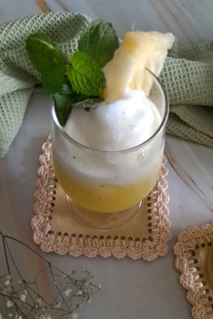 A glass of pineapple juice with mint on ice.